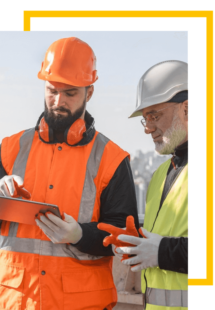 Duas pessoas trabalhando em uma obra de construção verificando uo andamento em um tablet