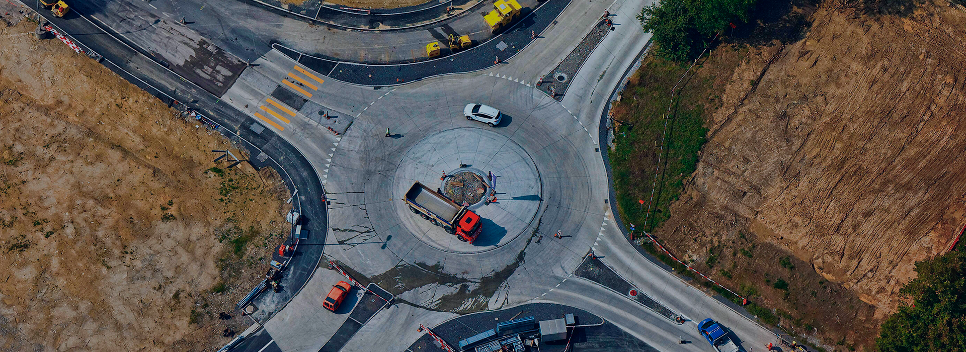 Engenheiro de capacete amarelo em frente a uma obra lendo informações em tablet.