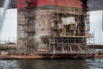 Trabalhadores sobre escadas e andaimes montados à margem de rio